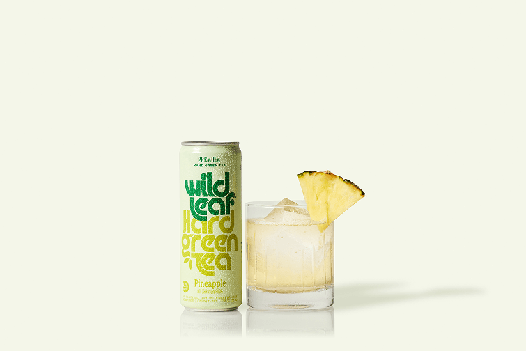 A can and glass of Pineapple Wild Leaf Hard Green Tea