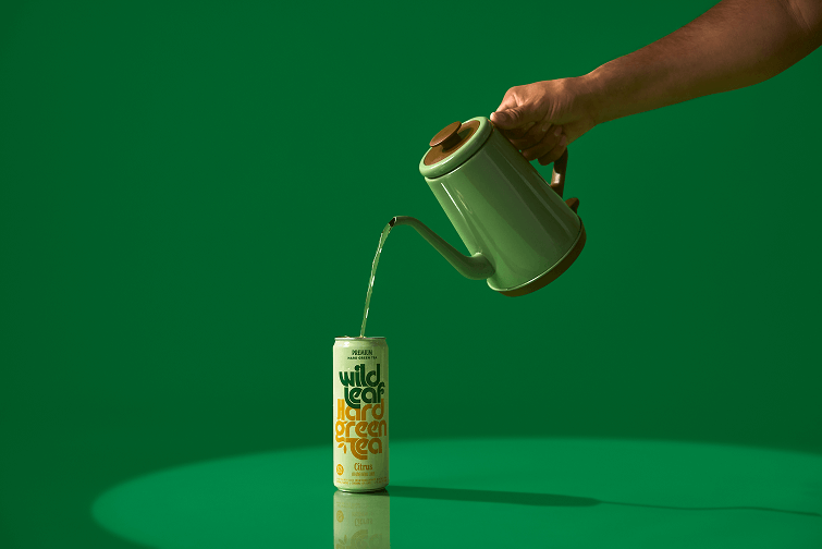 Tea being poured from a kettle into a can of Citrus Wild Leaf Hard Green Tea