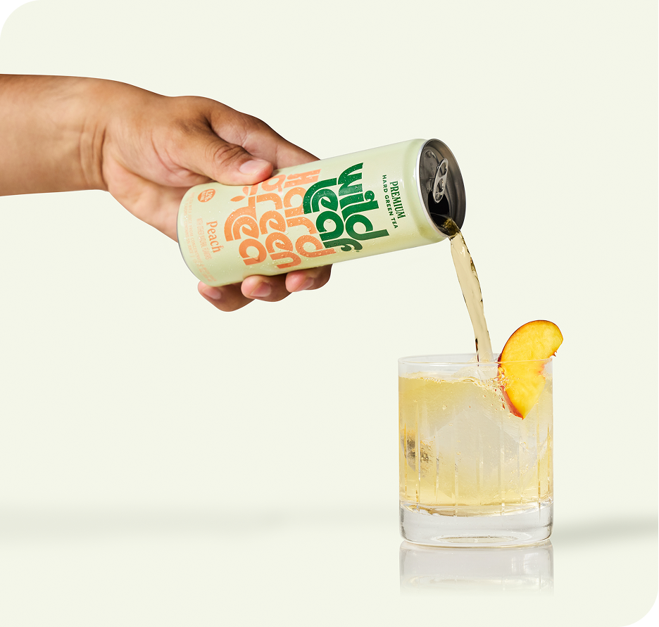 Peach Wild Leaf Hard Green Tea being poured from a can into a glass