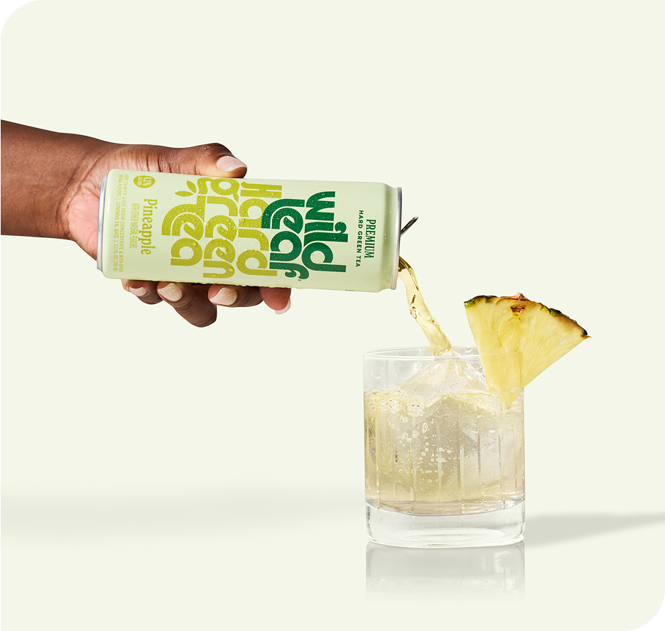 Pineapple Wild Leaf Hard Green Tea being poured from a can into a glass